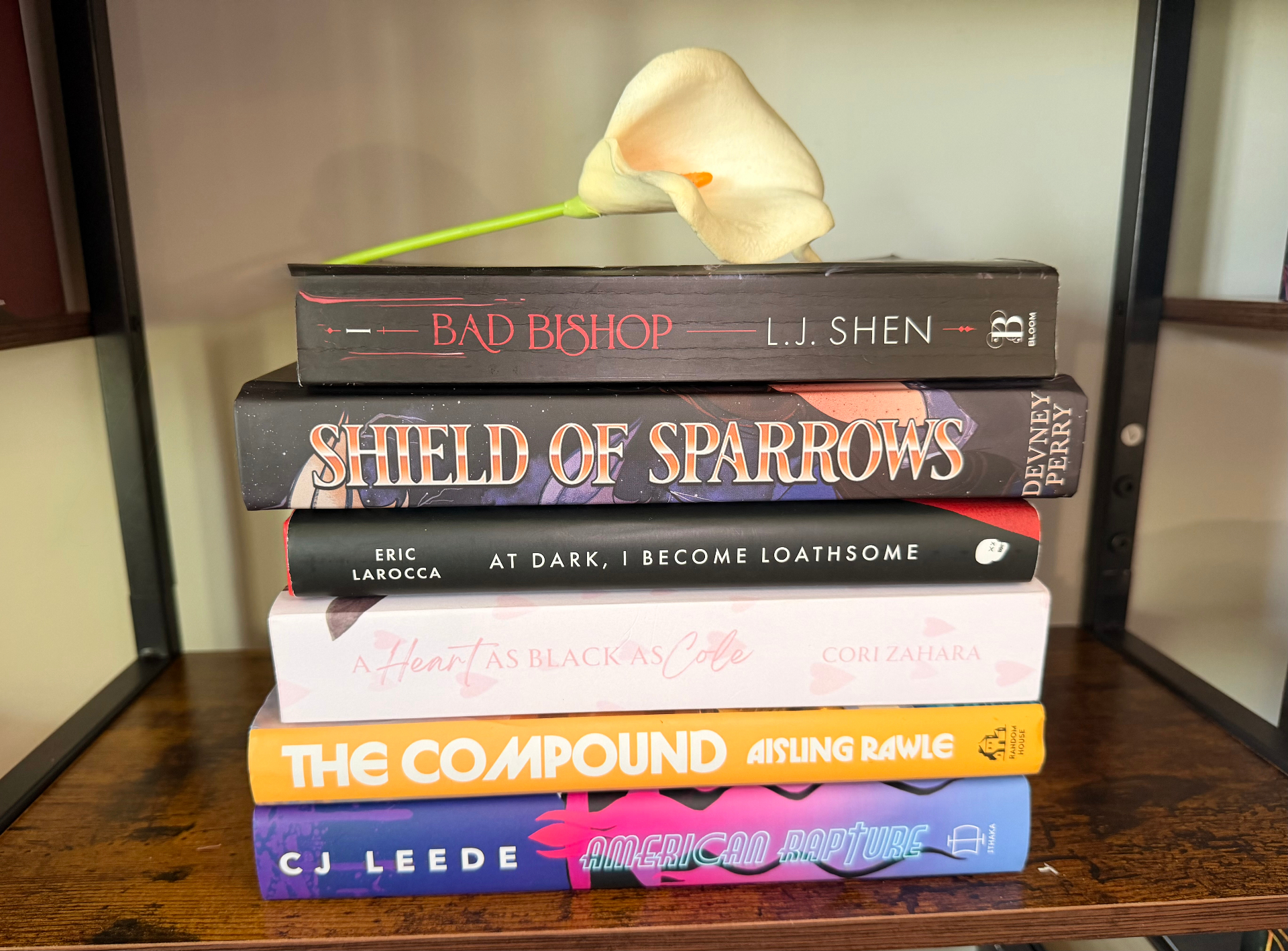 A stack of books wrapped in kraft paper with question marks and a pink rose on top