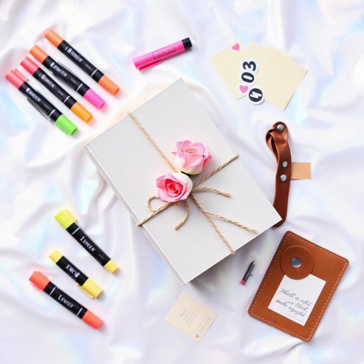 Flatlay of a wrapped book bundle with highlighters, tabs, leather bookmark and stickers